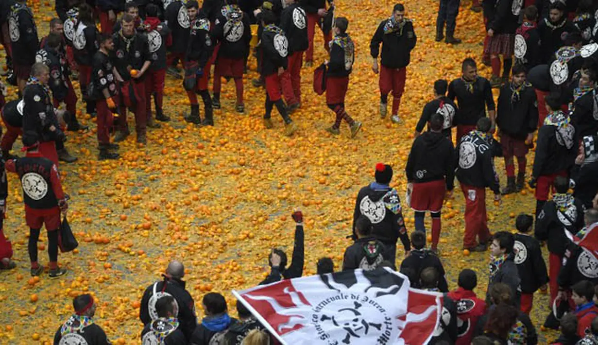 Sejumlah peserta berjalan diatas tumpukan jeruk yang hancur saat perayaan Karnaval Ivrea di Turin, Italia (16/2). (AFP PHOTO/Olivier MORIN)