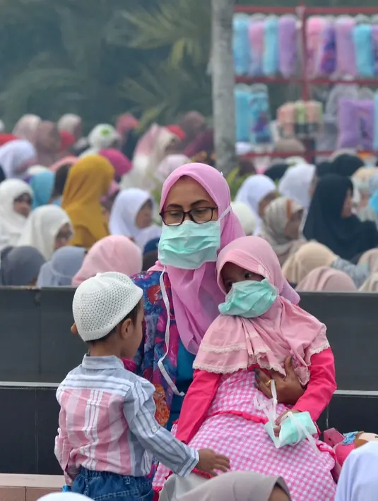 Umat muslim mengenakan masker saat mendengarkan ceramah usai melaksanakan salat Idul Adha di halaman Masjid Raya Annur, Kota Pekanbaru, Riau, Minggu (11/8/2019). Kabut asap imbas kebakaran hutan dan lahan (karhutla) menyelimuti pelaksanaan salat Idul Adha 2019 di Pekanbaru. (Wahyudi/AFP)