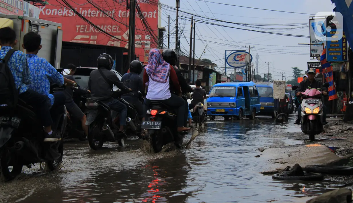 Sejumlah pengendara melintasi jalan berlubang dan tergenang air di Jalan Raya Pabuaran, Citayam, Depok, Rabu (26/2/2020). Kerusakan disebabkan oleh kubangan air yang menggenangi jalan tersebut pada musim hujan  yang melanda Jabodetabek dua bulan terakhir. (merdeka.com/magang/Muhammad Fayyadh)