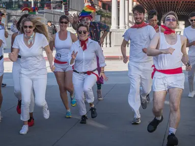 Peserta berdandan seperti badut mengajar pejalan kaki selama acara parodi tahunan "Running of the Clowns" i Pasadena, California pada 20 Oktober 2019. Lari dikejar kawanan badut ini merupakan parodi yang mengolok-olok lomba dikejar banteng di Spanyol. (Mark RALSTON / AFP)