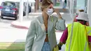 Gaya kasual Hailey Bieber dalam blazer dan bralette Jacquemus, dipasangkan dengan celana pendek Levi's, sepatu bot By Far, dan tas Prada. (FOTO: Instagram/stylememaeve).
