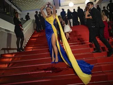Seseorang dengan warna Ukraina menuangkan zat merah ke tubuhnya pada pemutaran perdana film 'Aside' selama Festival Film Cannes ke-76, di Cannes, Prancis selatan, Minggu, 21 Mei 2023. (AP Photo/Daniel Cole)