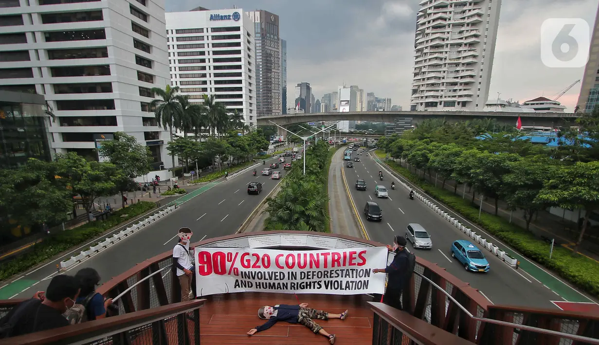 Sejumlah aktivis yang tergabung dalam Extintion Rebellion (XR) dan Walhi Jakarta melakukan aksi di JPO Pinisi, Jalan Jenderal Sudirman, Jakarta, Senin (14/11/2022). Aksi tersebut dilakukan untuk menyerukan kepada para pemimpin agar menghentikan “pencucian hijau” dan praktik ekonomi “business-as-usual” yang secara sistematis memperburuk krisis iklim dan mendorong umat manusia pada kehancuran ekologis & kepunahan massal. Negara-negara G20 turut menyumbang atas 80 persen emisi karbon dunia dan 60 persen populasi penduduk bumi. (Liputan6.com/Angga Yuniar)
