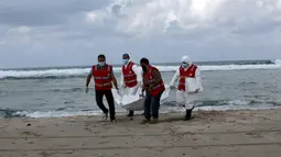 Kelompok Bulan Sabit Merah Libya membawa kantong mayat berisi jenazah, diduga imigran yang tewas tenggelam di pantai Khoms, sebelah timur Tripoli, Minggu (25/10). Sedikitnya 40 jasad telah ditemukan di pantai Libya. (REUTERS/Ismail Zitouny)
