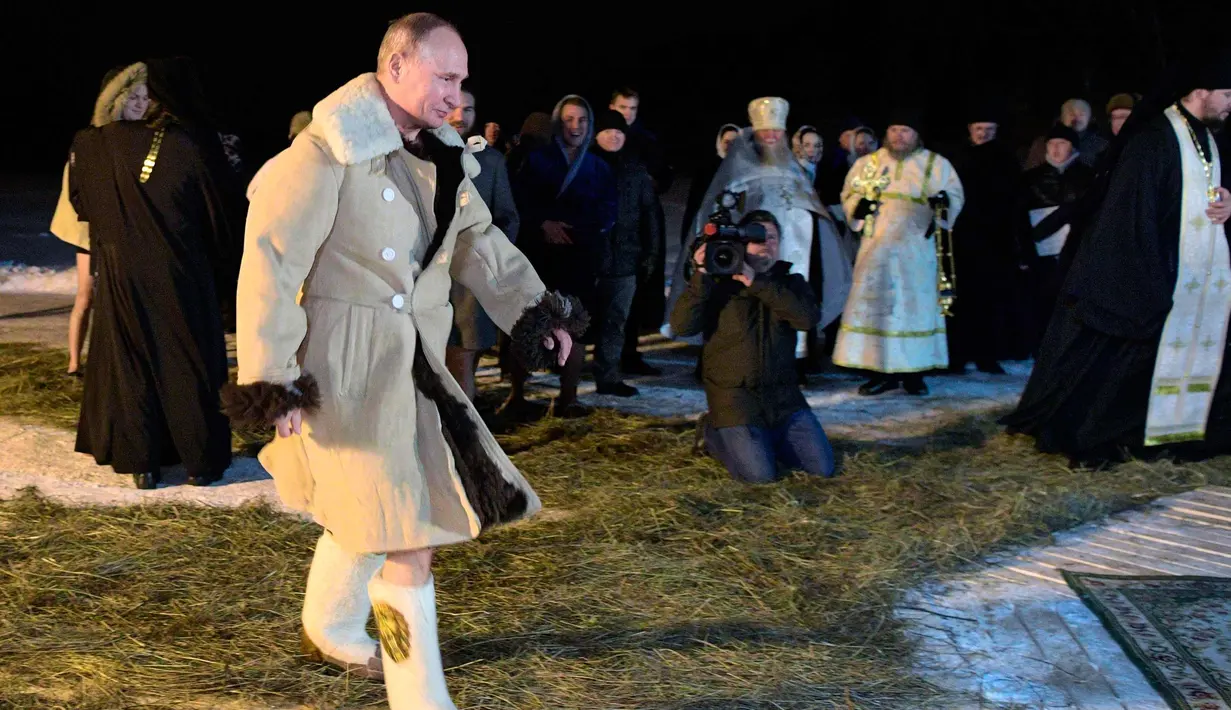 Presiden Rusia Vladimir Putin berpakaian mantel kulit domba berjalan untuk berendam di air dingin selama perayaan Hari Epiphany di Danau Seliger di desa Svetlitsa, Rusia (19/1). (Alexei Druzhinin, Sputnik, Kremlin Pool Photo via AP)