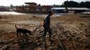 Joaquim Mendes da Silva, 73 tahun, berjalan bersama anjingnya di atas dasar danau Puraquequara yang kering di tengah kekeringan parah, di Manaus, negara bagian Amazonas, Brasil, Kamis, 5 Oktober 2023. (AP Photo/Edmar Barros)