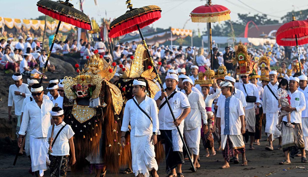 Prosesi sakral ini merupakan rangkaian menjelang Hari Raya Nyepi Tahun Baru Saka 1948 yang jatuh pada 19 Maret 2026. Tampak dalam foto, umat Hindu saat mengikuti upacara doa Melasti di salah satu pantai di Denpasar, Bali, pada Senin 16 Maret 2026. (SONNY TUMBELAKA/AFP)