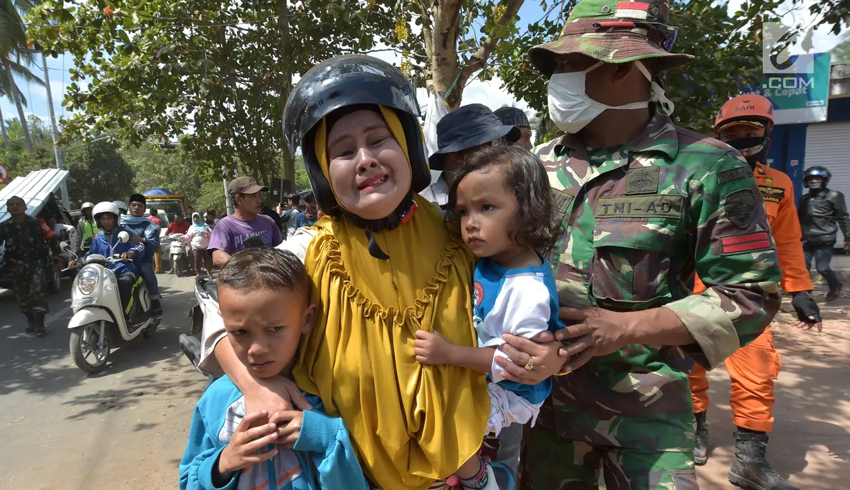 Anggota TNI mengavakuasi seorang wanita beserta kedua orang anak saat terjadi gempa susulan di Tanjung pulau Lombok, NTB, Kamis (9/8).Gempa susulan terjadi kembali dengan kekuatan 6,2 skala richter dikawasan tersebut.(AFP/ ADEK BERRY)