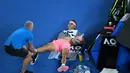 Petenis Spanyol, Rafael Nadal mendapat perawatan dari pelatihnya terkait cedera paha kanan pada perempat final Australia Terbuka 2018 di Melbourne, Selasa (23/1). Nadal mundur di set kelima saat menghadapi petenis Kroasia, Marin Cilic. (WILLIAM WEST/AFP)