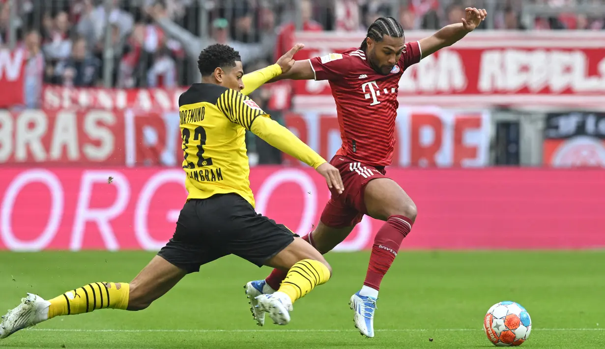 <p>Gelandang Borussia Dortmund Jude Bellingham (kiri) berebut bola dengan gelandang Bayern Munchen Serge Gnabry pada pekan ke-31 Bundesliga musim 2021/2022 di Allianz Arena, Minggu (24/4/2022) dini hari WIB. Bayern Munchen kembali menjadi juara Bundesliga usai menghajar rivalnya Borussia Dortmund 3-1. (Kerstin JOENSSON / AFP)</p>