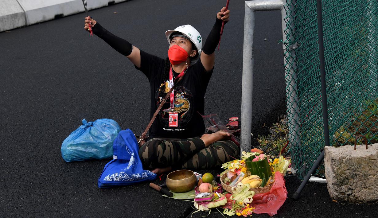 Seorang pawang hujan melakukan ritual saat sesi latihan bebas MotoGP Indonesia di Sirkuit Mandalika, Mandalika, Lombok Tengah, Nusa Tenggara Barat, Jumat (18/3/2022). (AFP/Bay Ismoyo)