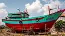 Nelayan menuntut pemerintah segera memberikan solusi, seperti penetapan harga BBM khusus, agar mereka bisa kembali melaut. Tampak dalam foto, para pria mengecat ulang perahu nelayan sementara kapal-kapal lain tetap berada di darat di Pelabuhan Juwana, Jawa Tengah, Rabu 6 Mei 2026. (Devi RAHMAN/AFP)