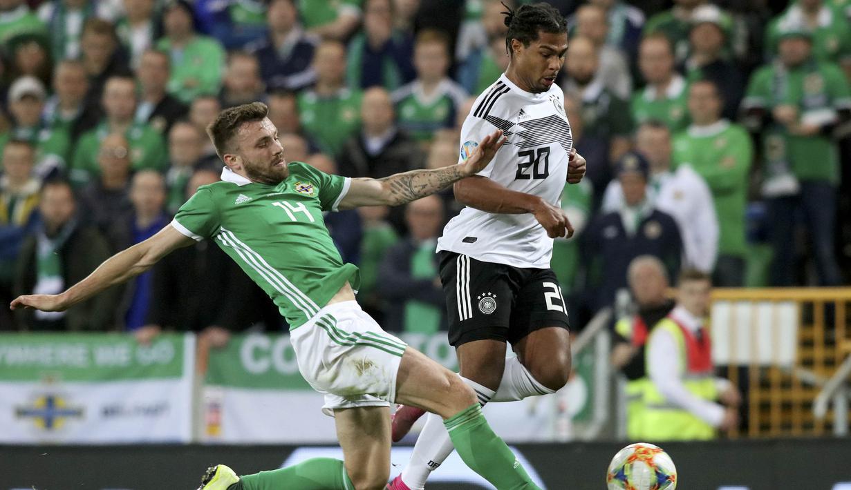 Gelandang Irlandia Utara, Stuart Dallas, berusaha menekel gelandang Jerman, Serge Gnabry, pada laga Kualifikasi Piala Eropa 2020 di Windsor Park, Belfast, Senin (9/9). Irlandia Utara kalah 0-2 dari Jerman. (AFP/Paul Faith)