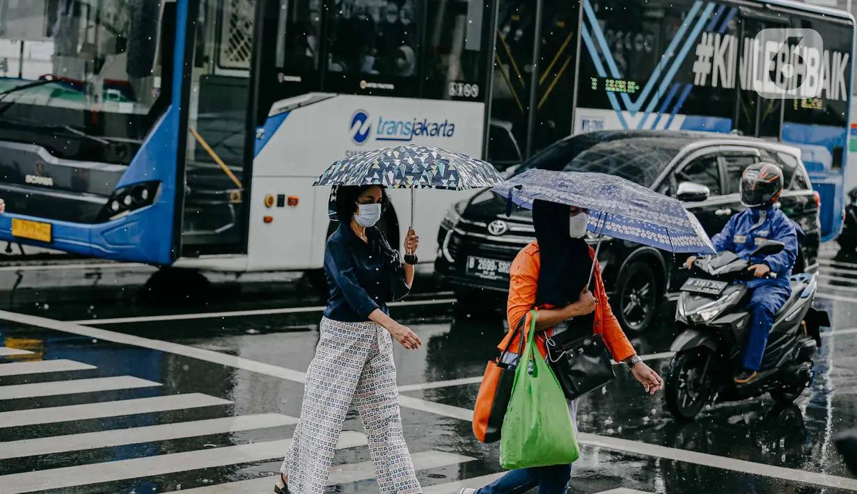 Pejalan kaki menggunakan payung saat hujan deras mengguyur kawasan Jalan Thamrin, Jakarta, Selasa (31/5/2022). Potensi cuaca ekstrem di sejumlah wilayah di Indonesia pada hari ini dipengaruhi oleh kemunculan bibit siklon tropis 92S di Samudera Hindia selatan Jawa Barat. (Liputan6.com/Faizal Fanani)
