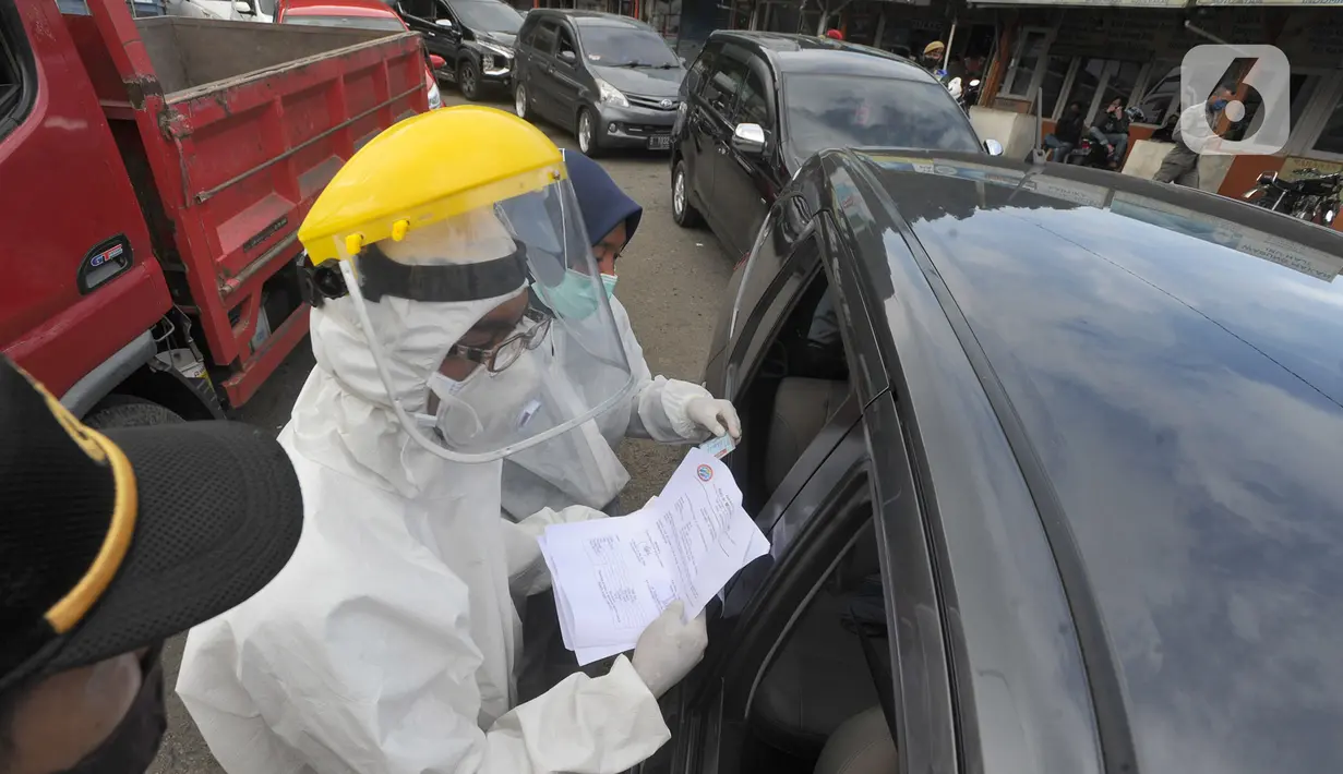 Petugas memeriksa surat keterangan lolos uji rapid test pada warga yang akan melakukan perjalanan di Pos Pam Puncak Pass, Jawa Barat, Minggu (17/5/2020). Ratusan kendaraan dipulangkan ke daerah asalnya dari wilayah Bogor Depok dan Jakarta karena melanggar PSBB parsial.  (merdeka.com/Arie Basuki)