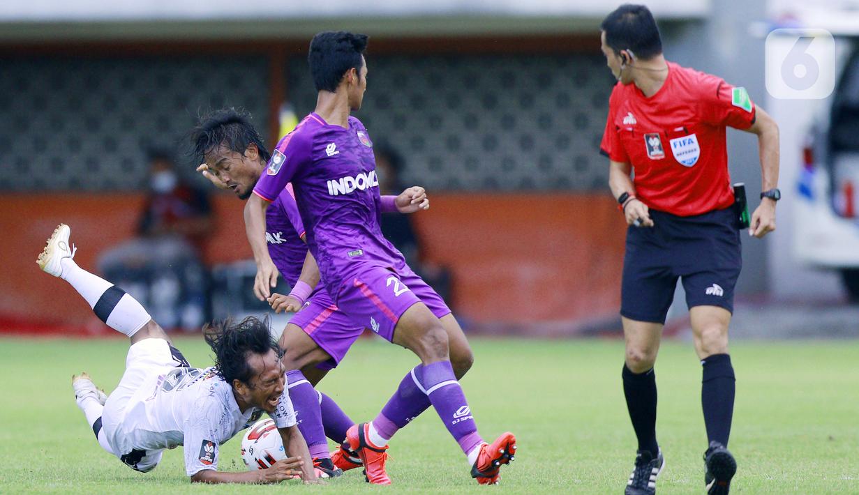 Gelandang Bali United Hariono (kiri) terjatuh saat berebut bola dengan pemain Persita Tangerang pada laga Piala Menpora 2021 di Stadion Maguwoharjo, Sleman, Jumat (2/4/2021). Laga berakhir imbang 1-1. (Bola.com/M Iqbal Ichsan)