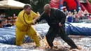 Dua orang pegulat beraksi saat mengikuti World Gravy Wrestling Championships ke-10 di Rose 'n' Bowl Pub di Inggris (28/8). Dalam pertandingan gulat ini, peserta mengenakan pakain unik saat bertanding. (AFP Photo/Oli Scarff)