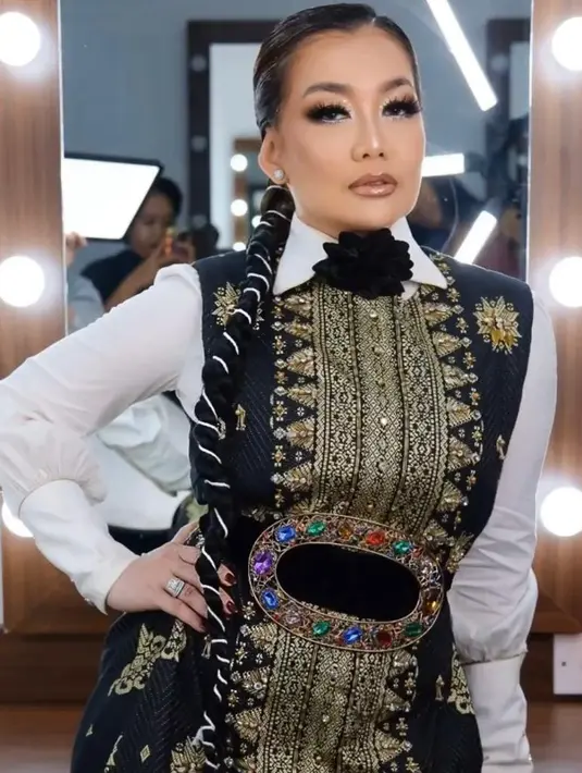 Reza Artamevia mengenakan baju songket modern nuansa hitam, putih, dan emas yang mewah. [@rezaartameviaofficial]