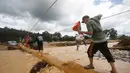 Evakuasi dan penyaluran bantuan darurat juga terus dilakukan untuk memenuhi kebutuhan logistik, air bersih, dan layanan kesehatan bagi para pengungsi. Tampak dalam foto, seorang pria memegang ayam sambil berjalan di atas kayu gelondongan yang digunakan sebagai jembatan darurat di sebuah desa yang terdampak banjir bandang di Batang Toru, Sumatera Utara, Senin 1 Desember 2025. (AP Photo/Binsar Bakkara)