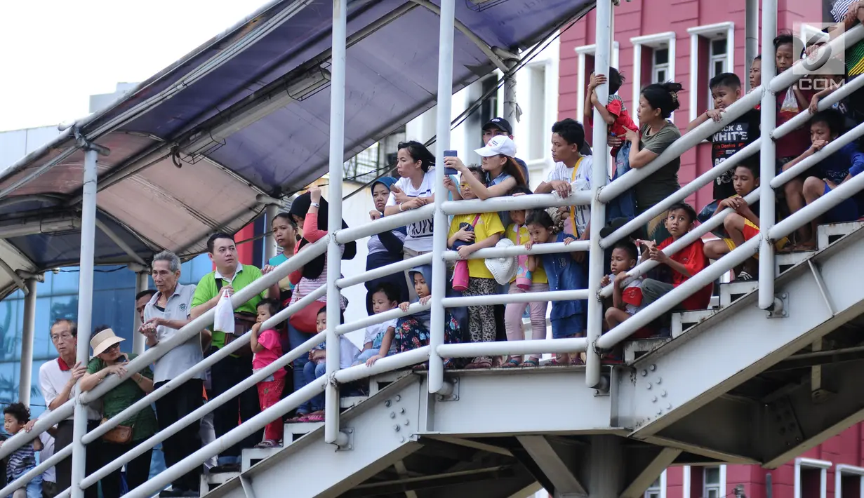 Warga memadati tangga salah satu JPO di ruas Jalan Gajah Mada, Jakarta saat menyaksikan karnaval Cap Go Meh 2018, Minggu (4/3). Beragam atraksi budaya ditampilkan dalam karnaval Cap Go Meh 2018 di kawasan Glodok Jakarta. (Liputan6.com/Helmi Fithriansyah)