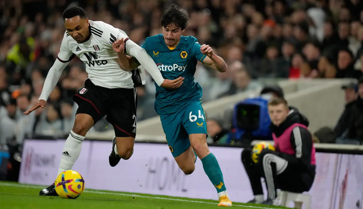 Pemain Fulham Kenny Tete (kiri) bersaing memperebutkan bola dengan pemain Wolverhampton Wanderers Hugo Bueno pada pertandingan sepak bola Liga Inggris di Stadion Craven Cottage, London, Inggris, 24 Februari 2023. Pertandingan berakhir imbang 1-1. (AP Photo/Kirsty Wigglesworth)