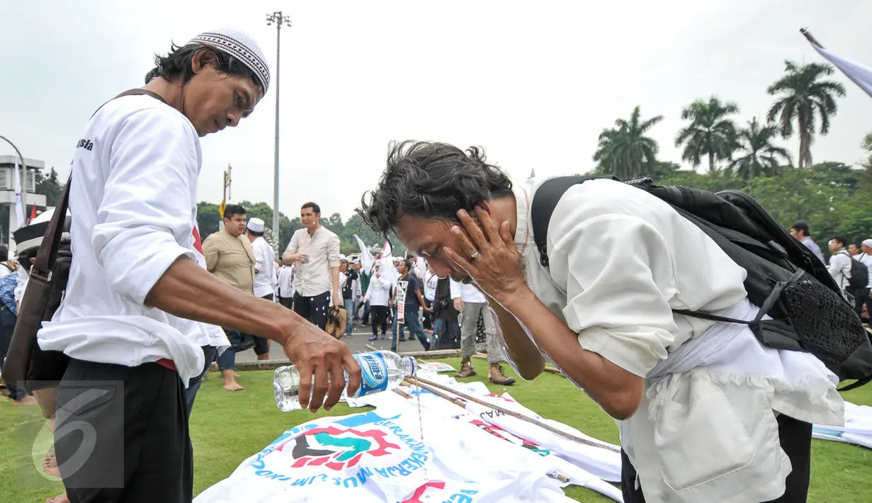 Demonstran menggunakan air mineral kemasan untuk wudhu sebelum menunaikan salat Jumat bersama di Bundaran Patung Kuda, Jakarta, Jumat (4/11). Sebagian massa demonstan gelar salat Jumat di area Bundaran Patung Kuda. (Liputan6.com/Yoppy Renato)