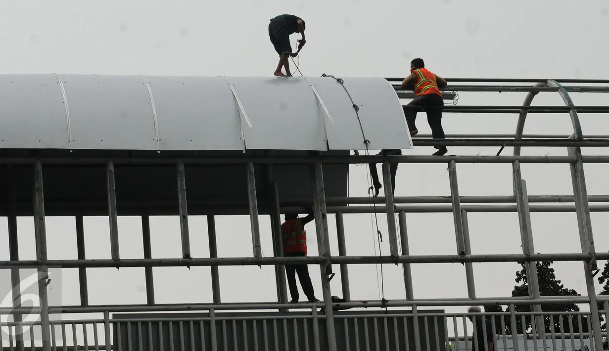 Pekerja melakukan pemasangan atap Jembatan Penyebrangan Orang (JPO) di Jalan Kasblanca, Jakarta, Selasa (22/11). Pemerintah Provinsi DKI Jakarta menargetkan perbaikan JPO tak layak segera rampung. (Liputan6.com/Helmi Fithriansyah)