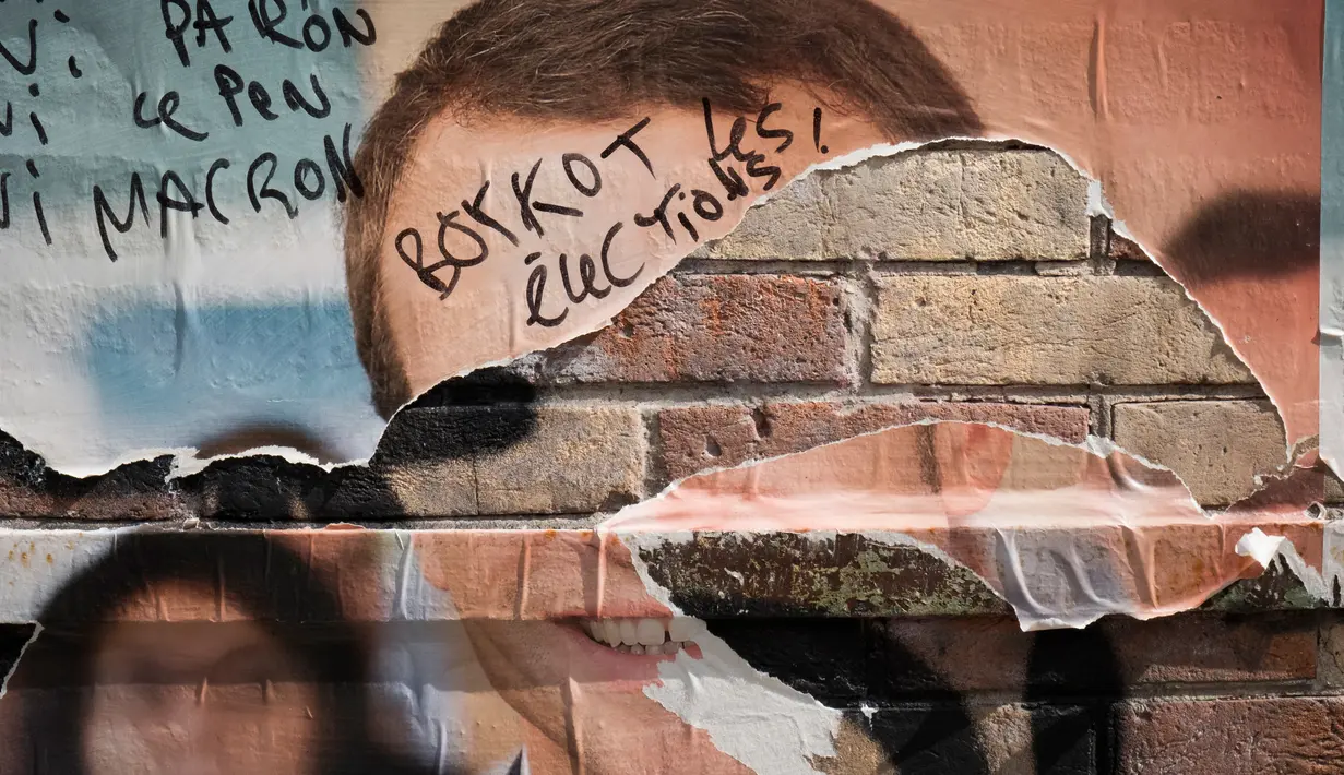 Poster Capres Prancis,  Emmanuel Macron terlihat rusak di Paris, Selasa (2/5). Sejumlah poster capres Prancis lainnya juga tampak rusak yang diduga dilakukan oleh orang yang tidak suka dengan mereka. (AFP PHOTO / JOEL SAGET)
