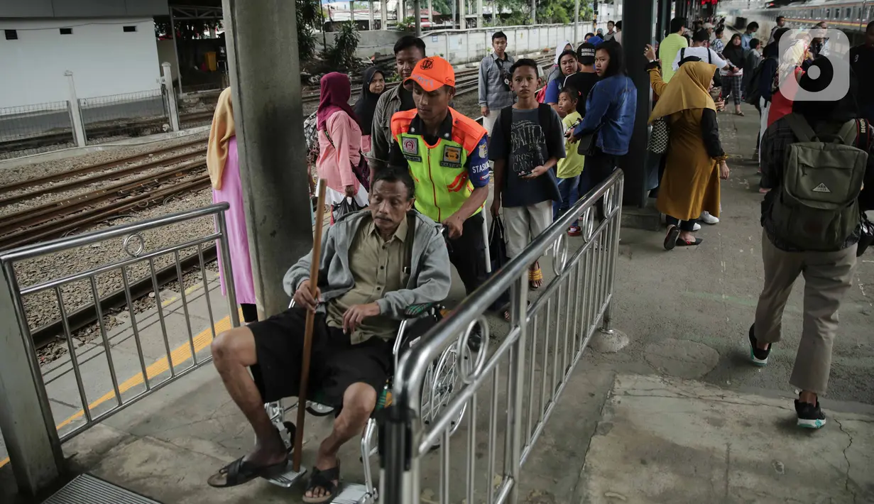 Petugas membantu calon penumpang berkursi roda di Stasiun Tanah Abang, Jakarta, Minggu (29/12/2019). PT KCI menambah jam operasional KRL hingga pukul 03.00 WIB pada 1 Januari 2020. (Liputan6.com/Faizal Fanani)