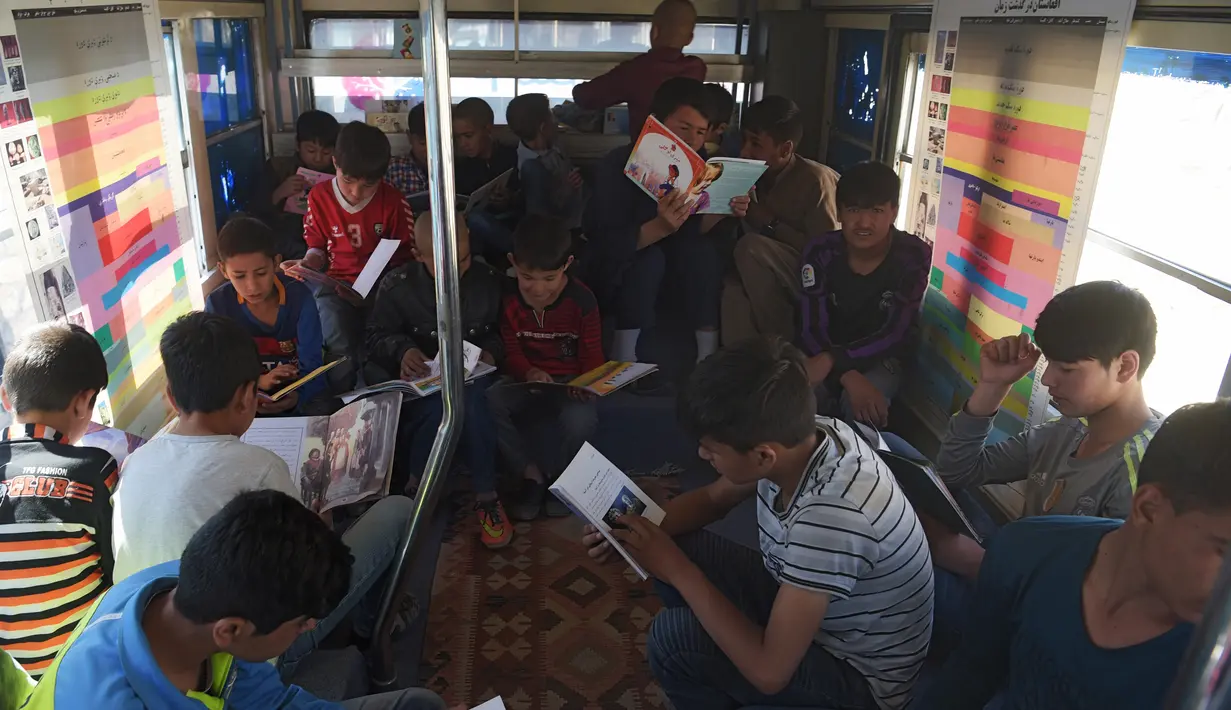 Anak-anak Afghanistan membaca buku dalam bus yang dijadikan perpustakaan keliling di Kabul, 4 April 2018. Bus keliling itu digunakan sebanyak 300 anak setiap hari dengan menggunakan kendaraan yang disewa dari perusahaan bus milik negara. (AFP/Shah MARAI)