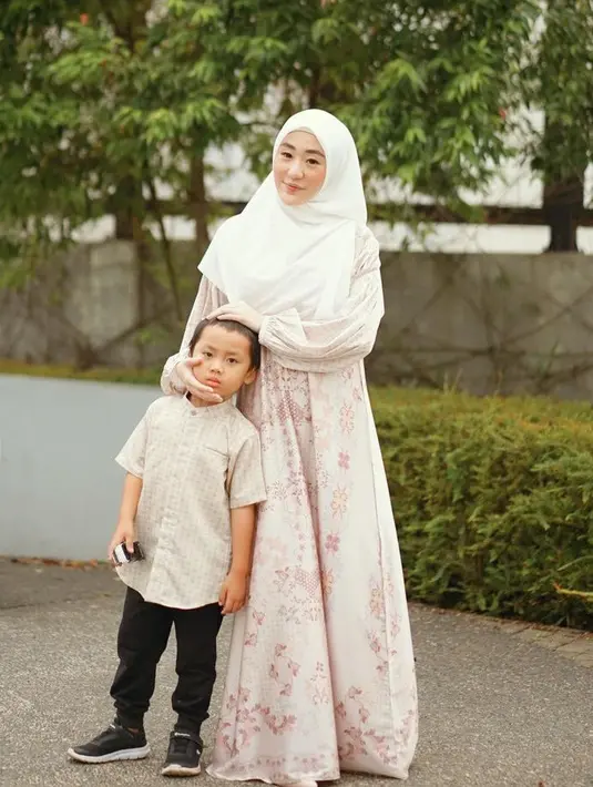 Larissa Chou tampil dengan gamis warna pastel dipadukan kerudung putih, sedangkan si kecil mengenakan baju koko dipadukan celana hitamnya. [@larissachou]