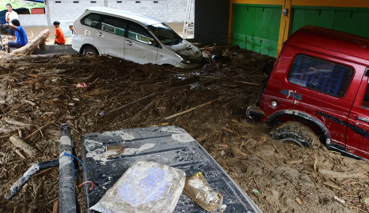 Mobil-mobil terjebak lumpur di daerah yang terkena banjir bandang di Masamba, Sulawesi Selatan, Rabu (15/7/2020). Banjir bandang yang terjadi akibat tingginya curah hujan itu mengakibatkan 16 orang meninggal dunia, sementara ratusan rumah rusak berat dan hilang. (AP/Khaizuran Muchtamir)