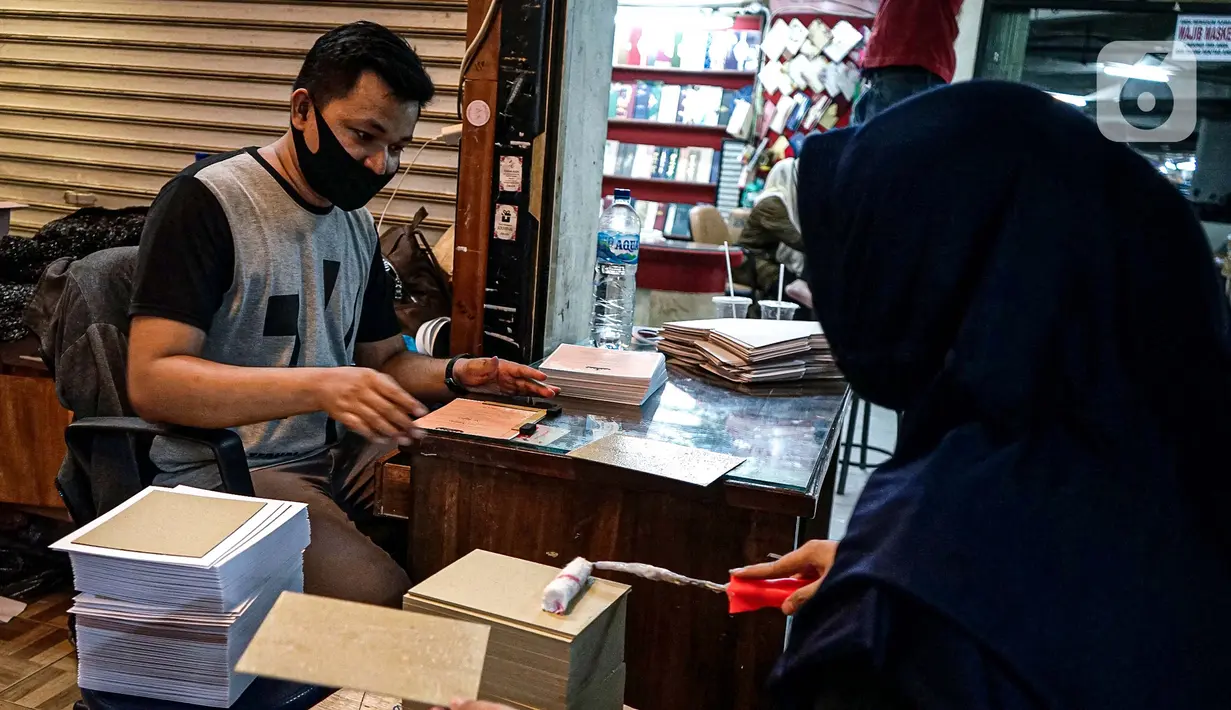 Aktivitas pedagang kertas undangan pernikahan di Pasar Tebet, Jakarta, Kamis (22/7/2020). Adanya larangan membuka toko dan juga berkerumun seperti pesta pernikahan menyebabkan pendapatan dari usaha percetakan ini turun drastis hingga 80 persen selama pandemi Covid-19. (Liputan6.com/Faizal Fanani)