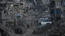 Pembukaan kembali perlintasan Rafah sangat krusial untuk mengisi kembali stok bantuan yang terkuras selama dua tahun konflik. Tampak dalam foto, warga Palestina berjalan di tengah bangunan yang hancur akibat serangan udara dan darat Israel di Kota Gaza, Selasa 6 Januari 2026. (AP Photo/Jehad Alshrafi)
