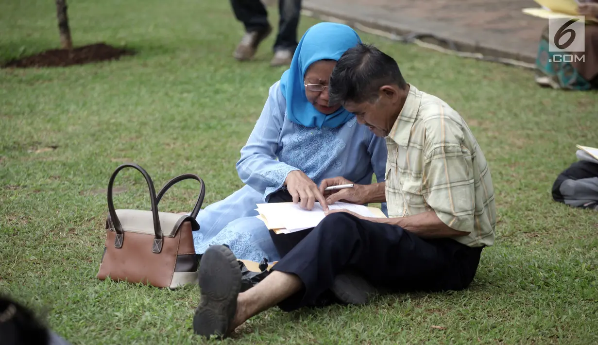 Seorang wanita mengajari pasangannya cara mengisi formulir dalam Festival Keimigrasian 2018 di Lapangan Barat Daya Monas, Jakarta, Minggu (21/1). Panitian menyediakan 1.600 formulir pembuatan paspor. (Liputan6.com/Arya Manggala)