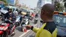 Petugas Sudin Bina Marga Jakarta Barat membagikan masker dan pasta gigi kepada pengendara motor di Jalan KS Tubun, Petamburan, Kamis (23/5/2019). Sisa gas air mata untuk membubarkan massa dalam kericuhan aksi 22 Mei masih terasa dan mengganggu aktvitas pengguna jalan (Liputan6.com/Immanuel Antonius)