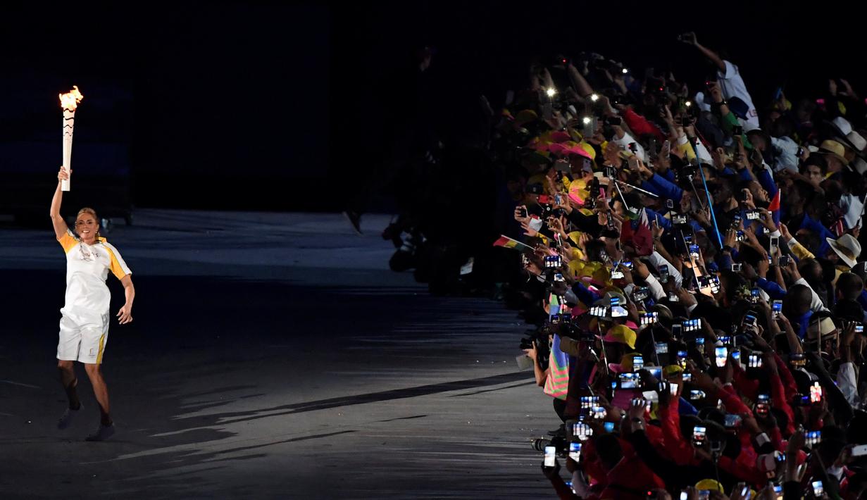 Mantan atlet Brasil, Hortencia Marcari, membawa obor api olimpiade memasuki stadion saat Pembukaan Olimpiade Rio 2016 di Stadion Maracana, Rio de Janeiro, Brasil, (5/8/2016). (AFP/William West)
