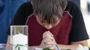 Trent Bolin (13) berdoa di depan lilin untuk mengenang korban penembakan di sekolah Santa Fe, Texas, Amerika serikat, Jumat (18/5). (Stuart Villanueva The Galveston County Daily News via AP)