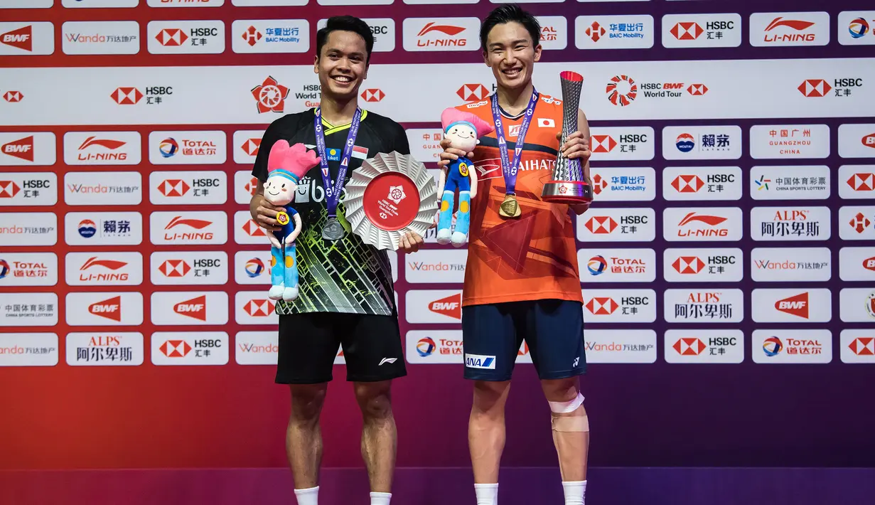 Tunggal putra Indonesia, Anthony Ginting, naik podium bersama tunggal Jepang, Kento Momota, pada BWF World Tour 2019 di Tianhe Gymnasium, Guangzhou, Minggu (15/12). Ginting kalah 21-17, 17-21 dan 14-21 dari Momota. (AFP/STR)