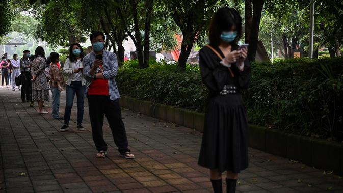 Warga mengenakan masker menunggu dalam barisan untuk tes virus corona di lingkungan di Wuhan, provinsi Hubei, China, Jumat (15/5/2020). Pihak berwenang Kota Wuhan menggelar tes massal terhadap 11 juta warganya untuk mencegah gelombang kedua pandemi Covid-19. (Hector RETAMAL/AFP)