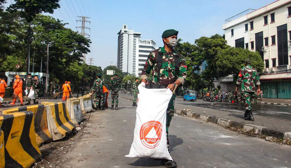 Mereka tampak menggunakan alat seadanya untuk membersihkan abu sisa pembakaran yang dilakukan oleh massa pada saat demo di kawasan tersebut. (merdeka.com/Arie Basuki)