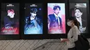 Seorang perempuan melewati layar listrik yang menunjukkan anggota boyband K-pop, BTS, di di stasiun kereta bawah tanah di Seoul, Selasa (1/9/2020). Bangtan Boys (BTS) menjadi artis Korea Selatan pertama yang berhasil menempati puncak Billboard Hot 100 dengan lagu Dynamite. (Jung Yeon-je/AFP)