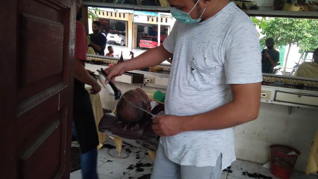 Seorang barber tengah memangkas rambut pelanggannya (Liputan6.com/Rino Abonita)
