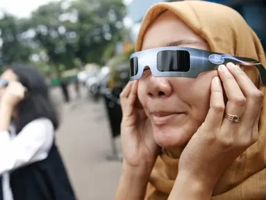 Petugas mencoba kacamata khusus yang akan digunakan saat pengamatan Gerhana Matahari Total (GMT) di Planetarium TIM Jakarta, Selasa (8/3). Planetarium akan memfasilitasi warga yang hendak menyaksikan fenomena gerhana matahari. (Liputan6.com/Faizal Fanani)