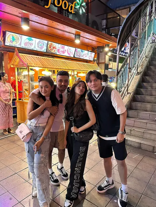 Seperti potret ini, kala berburu kuliner Thailand, keduanya tampil kompak banget pakai outfit nuansa monokrom. Rizky dengan padu padan kaus, vest, dan celana pendek. Sementara Mahalini dengan tanktop dan celana kargo hitam. [@rizkyfbian]