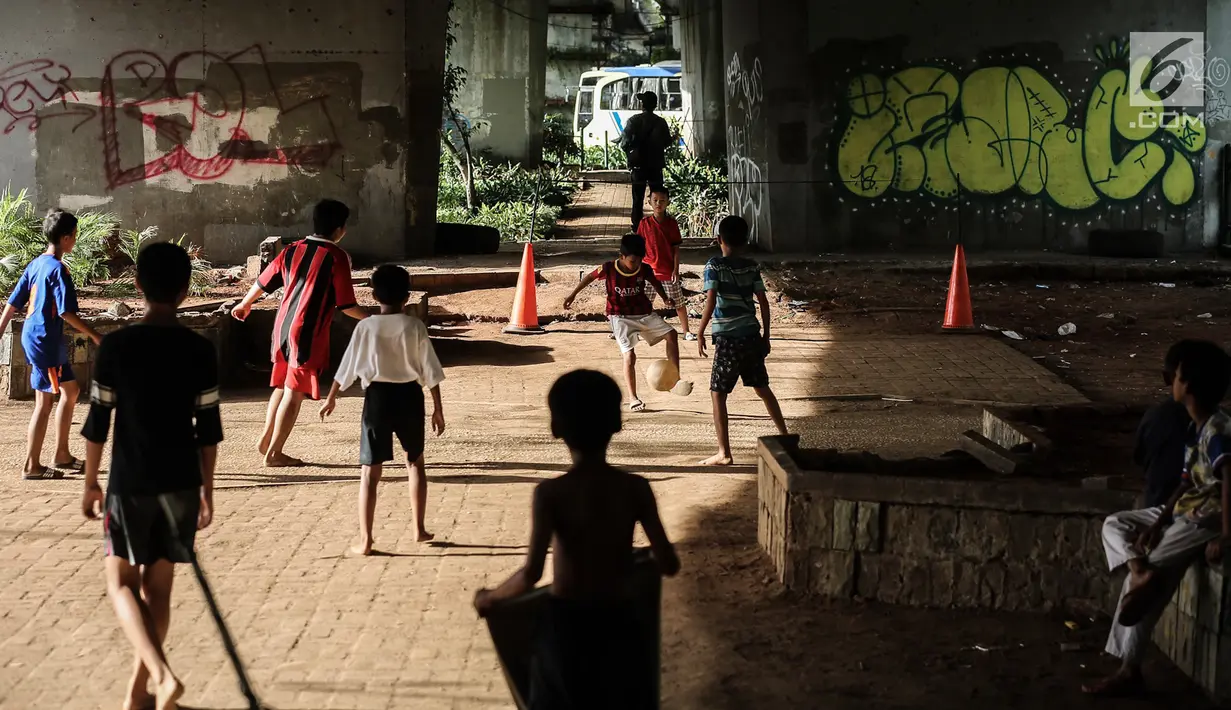 Anak-anak bermain sepak bola di kolong jembatan layang Tanah Abang, Jakarta, Kamis (15/11). Mereka bermain dengan suasana lalu lintas kendaraan yang cukup ramai. (Liputan6.com/Fery Pradolo)