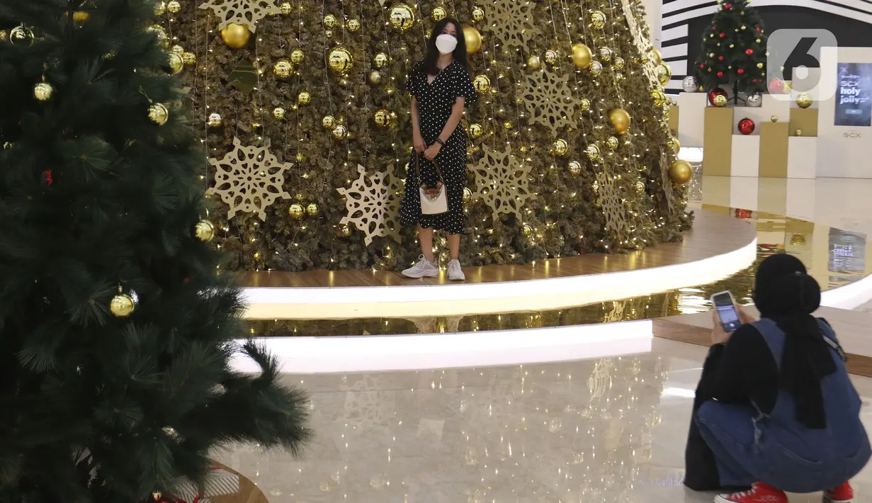 Pengunjung foto di dekat pohon Natal di Senayan City, Jakarta, Selasa (14/12/2021). Senayan City mempersembahkan FESTIVE LUMINOUS dalam rangkaian momen perayaan Natal dan Tahun Baru 2022. (Liputan6.com/Faizal Fanani)