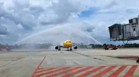 Water salute dari petugas pemadam Bandara SSK II Pekanbaru terhadap maskapai dari Singapura yang baru mendarat. (Liputan6.com/M Syukur)
