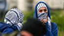 Seorang wanita Palestina menutupi wajahnya dengan kaffiyeh selama bentrokan dengan tentara Israel dalam demonstrasi untuk memperingati Hari Tanah di Tepi Barat, Sabtu (30/3).(Photo by ABBAS MOMANI/AFP)