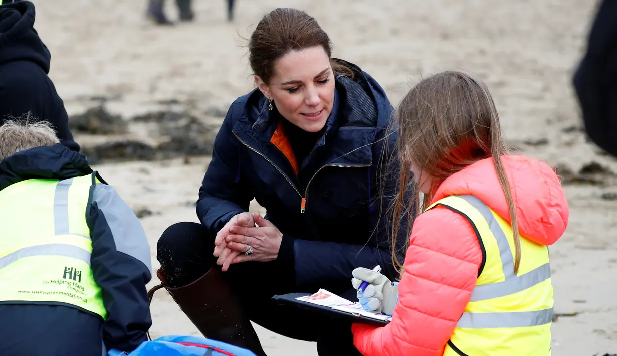 Kate Middleton, Duchess of Cambridge, berbincang dengan seorang anak sekolah saat membersihkan sampah di pantai Newborough di Wales (8/5). Pangeran William dan Kate Middleton melakukan kunjungan ke pantai Newborough untuk membersihkan sampah bersama anak-anak sekolah. (Reuters/Phil Noble)